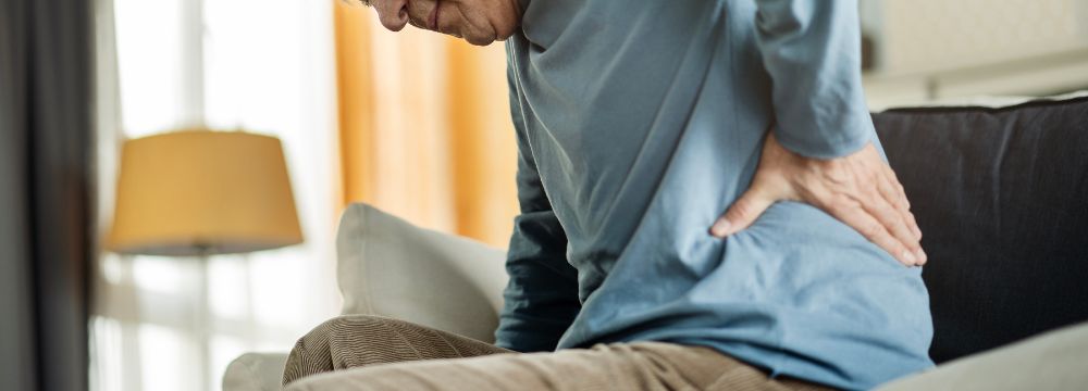 Man putting hand on back struggling with kidney stone pain