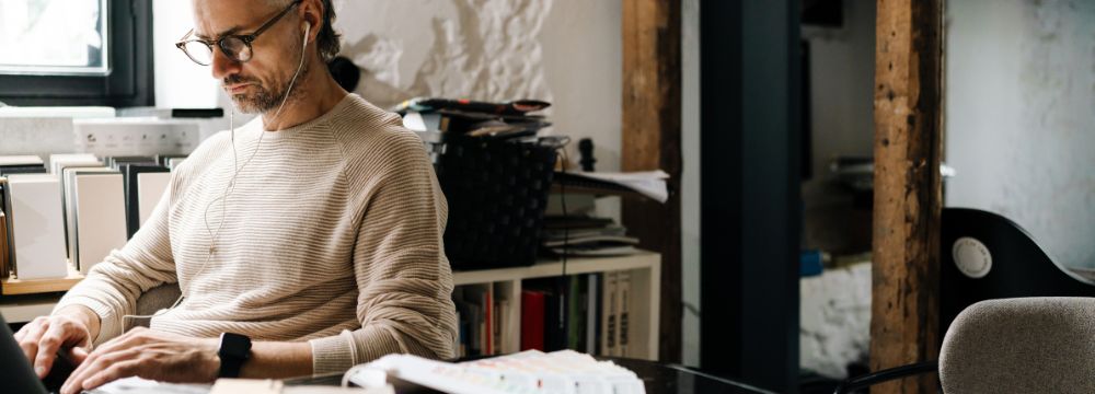 Man working at desk in at home office space, pondering about options for penile implants